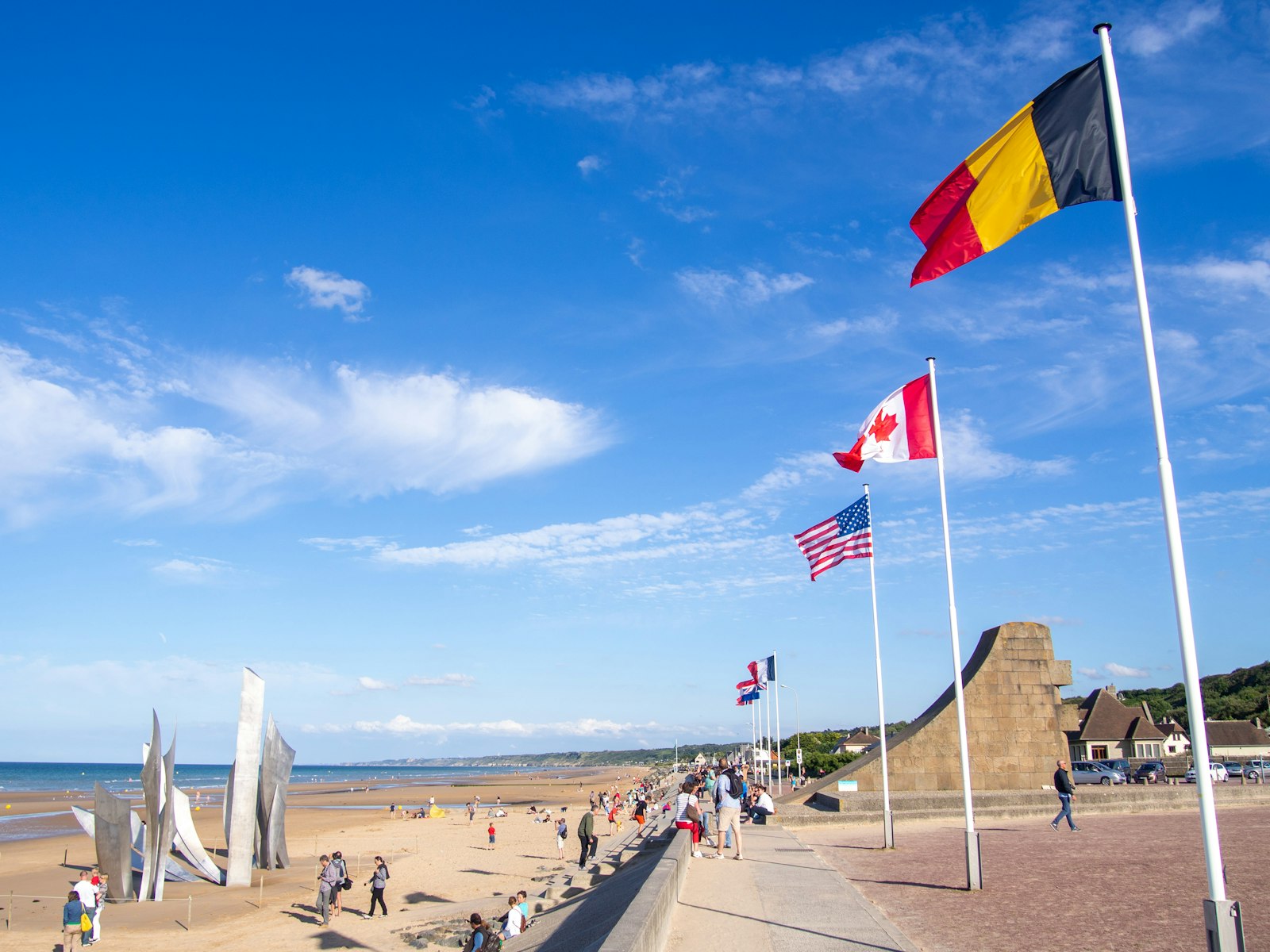 Allied flags along the Omaha Beach esplanade at Saint-Laurent-sur-Mer, with the Les Braves sculpture on the sand